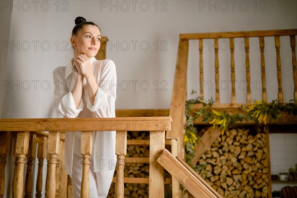 A woman looks thoughtfully into the distance while standing on a flight of stairs, resting her