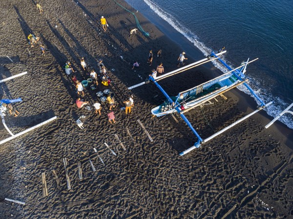 Fishermen unload their catch from their outrigger boat in the morning. Amed, Karangasem, Bali,
