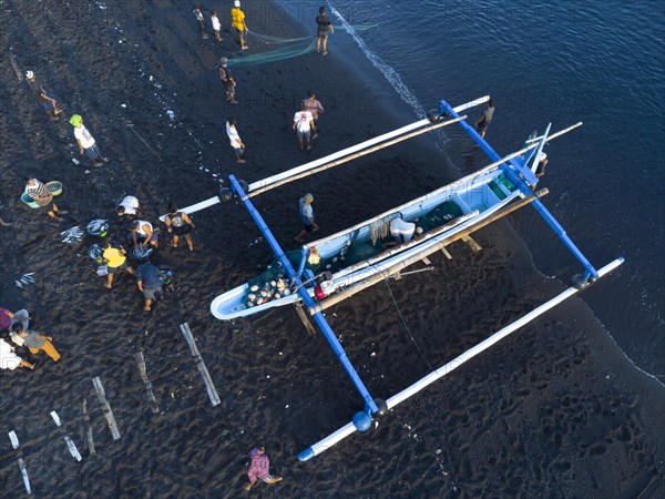 Fishermen unload their catch from their outrigger boat in the morning. Amed, Karangasem, Bali,