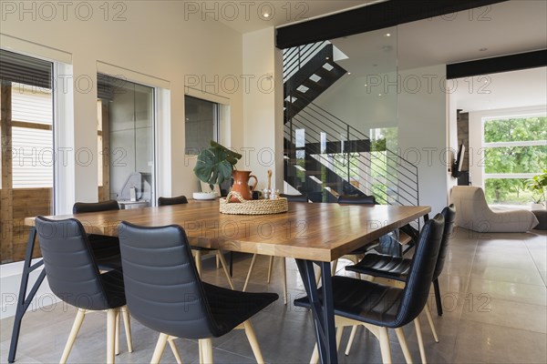American walnut wood dining table and black leather sitting chairs with ash wood legs in dining