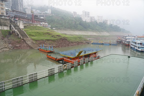 Yichang, Hubei Province, China, Asia, Foggy day with view of ships at a jetty along a river with a