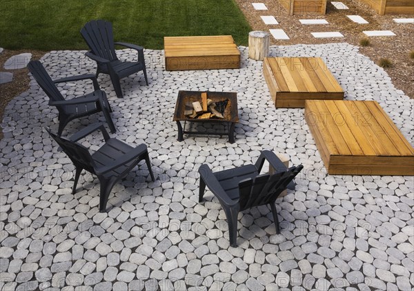 Grey paving stone patio with black Adirondack sitting chairs, slightly raised flat rectangular red