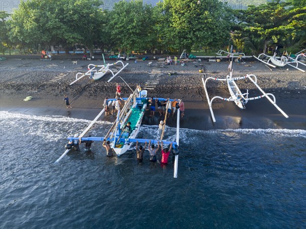 Fishermen unload their catch from their outrigger boat in the morning. Amed, Karangasem, Bali,