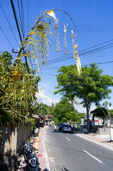 Jewellery artfully woven from palm leaves on bamboo poles for a festival, on a village street in