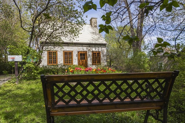 Old circa 1750 Canadiana style fieldstone house facade with brown stained wooden windows, door and