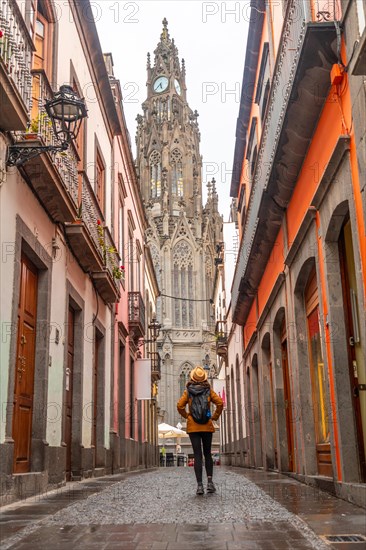 A tourist woman walking along a beautiful street next to the Church of San Juan Bautista, Arucas