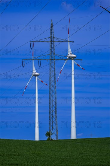 Power pylon with high-voltage lines and wind turbines at the Avacon substation Helmstedt,