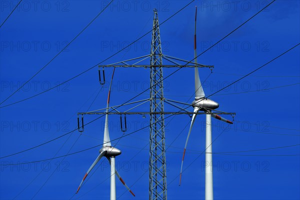 Power pylon with high-voltage lines and wind turbines at the Avacon substation Helmstedt,