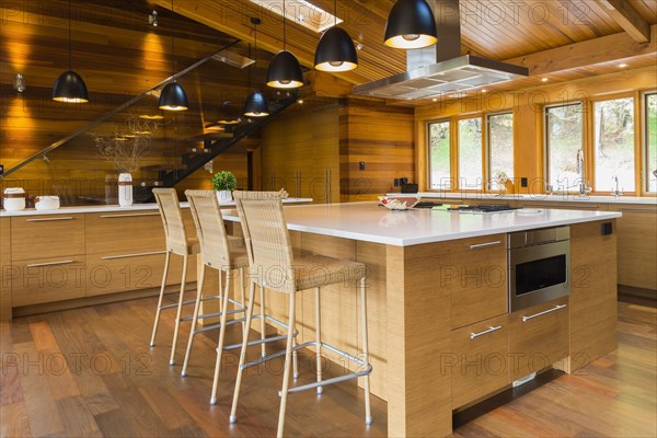 Bamboo wood island with white quartz countertops and high wicker chairs, buffet in kitchen with Ipe