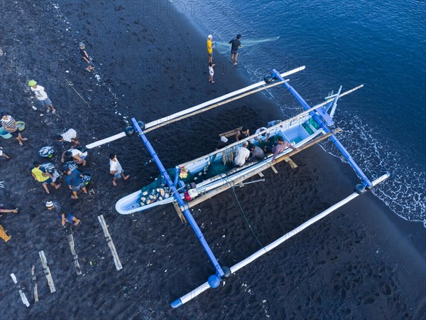 Fishermen unload their catch from their outrigger boat in the morning. Amed, Karangasem, Bali,
