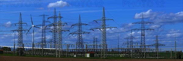 Power pylons with high-voltage lines and wind turbines at the Avacon substation in Helmstedt,