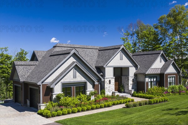 Contemporary natural stone and brown stained wood and cedar shingles clad luxurious bungalow style
