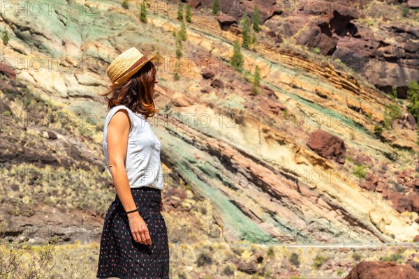 A tourist woman at the Natural Monument Azulejos de Veneguera or Rainbow Rocks in Mogan, Gran