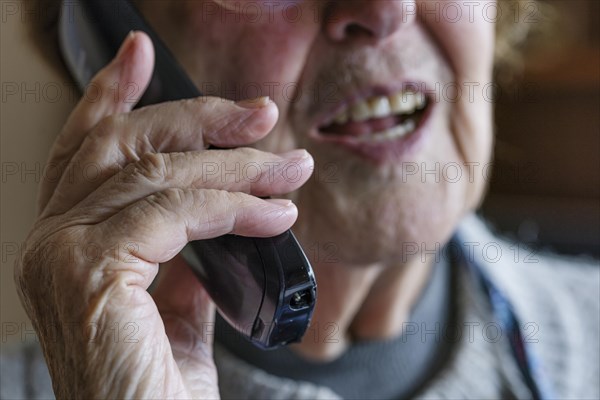 Mouth, hands and telephone receiver of a senior citizen making a phone call, close-up, Cologne,