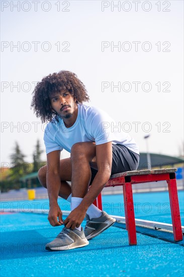 Vertical portrait of a concentrated young african american running getting ready to train tying her
