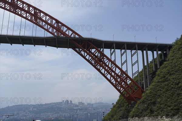 Chongqing, Chongqing Province, A high red bridge spans a river, with a city in the sunny