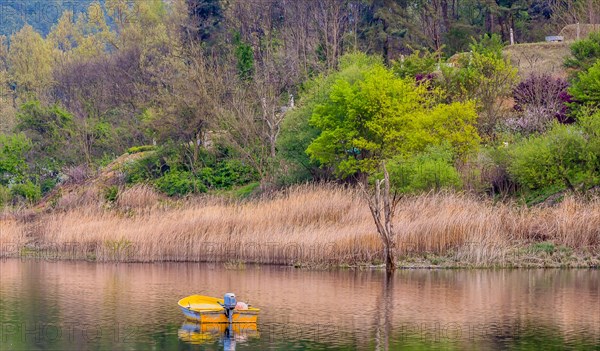 Small yellow metal fishing boat with small engine mount floating peacefully on a lake in South