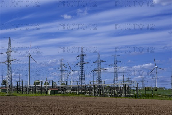 Power pylons with high-voltage lines and wind turbines at the Avacon substation in Helmstedt,