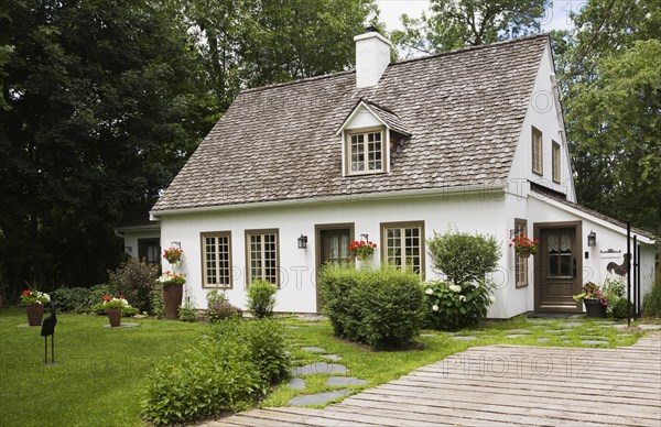 Old circa 1886 white with beige and brown trim Canadiana cottage style home facade with wood plank