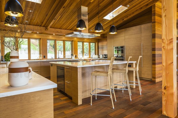 Bamboo wood buffet and island with white quartz countertops and high wicker chairs, cabinets in
