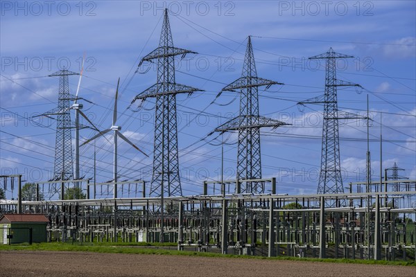 Power pylons with high-voltage lines and wind turbines at the Avacon substation in Helmstedt,