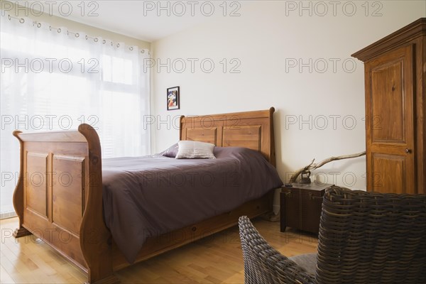 Antique wooden queen size sleigh bed in master bedroom inside a renovated ground floor apartment in
