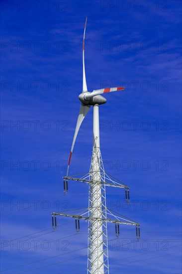 Electricity pylon with high-voltage lines and wind turbine at the Avacon substation Helmstedt,