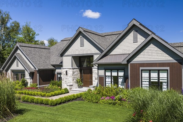Contemporary natural stone and brown stained wood and cedar shingles clad luxurious bungalow style