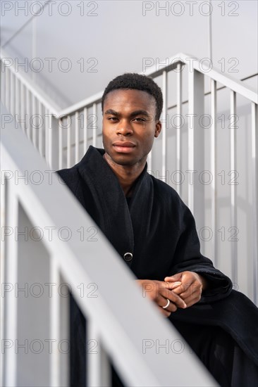 Vertical portrait of a handsome african american model with black warm clothes sitting on outdoor