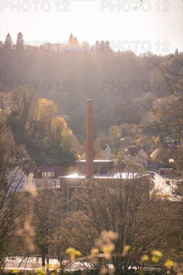 Industrial chimney rises into a sky at sunset with trees, spring, Calw, Black Forest, Germany,