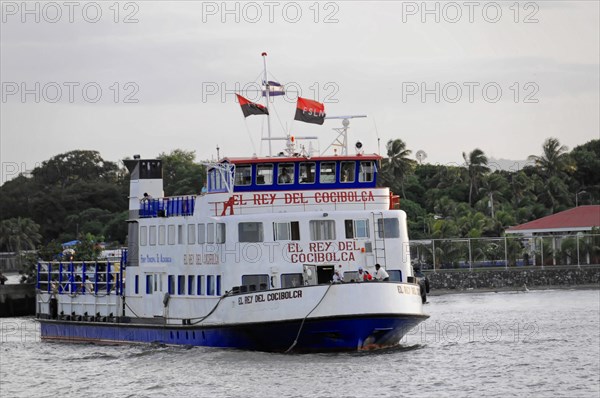 Lake Nicaragua, Ometepe Island in the background, Illuminated ferry at the dock at dusk with a
