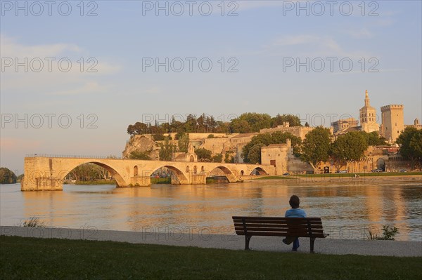 Woman on a park bench on the banks of the Rhone, Pont Saint Benezet bridge, Papal Palace and