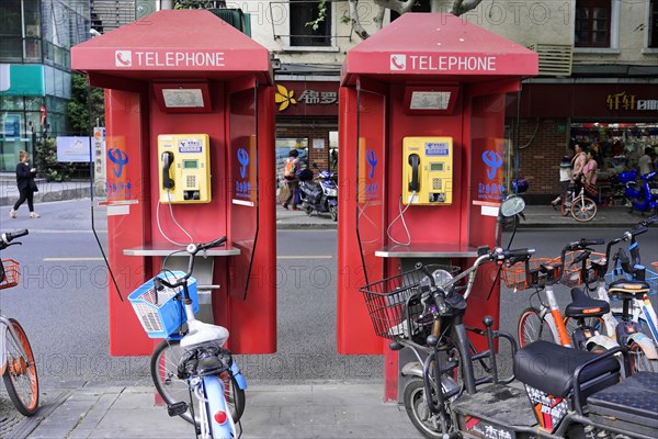 Shanghai, China, Two red telephone booths on a pavement next to parked bicycles, Shanghai, People's