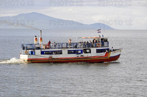 Lake Nicaragua, behind the island of Ometepe, ferry with passengers on the open sea, waving flag