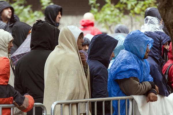 Syrian refugees wait for their registration in cold and wet weather at the Berlin State Office for