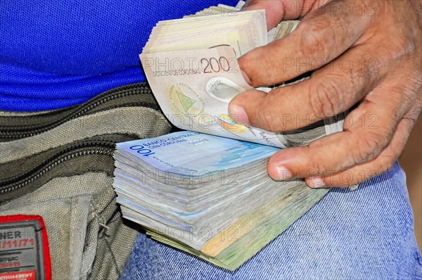 Leon, Nicaragua, hands counting Honduran Lempira banknotes in front of an open bag, Central