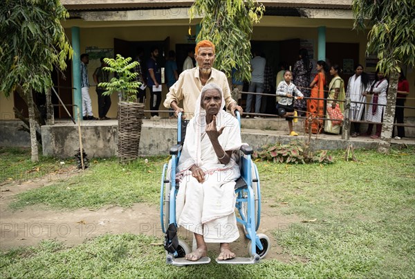 BOKAKHAT, INDIA, APRIL 19: A elderly woman in wheelchair show her marked finger after casting vote