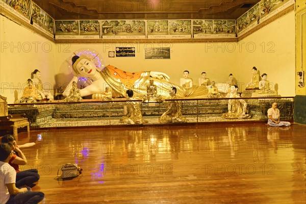 Shwedagon Pagoda, Yangon, Myanmar, Asia, Reclining Buddha statue in a temple, surrounded by praying