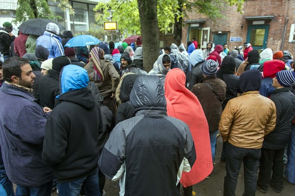 Syrian refugees wait for their registration in cold and wet weather at the Berlin State Office for