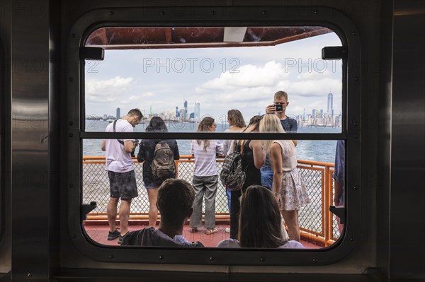 Tourists on the Staten Island ferry with a view of the Manhattan skyline, New York City, USA, New
