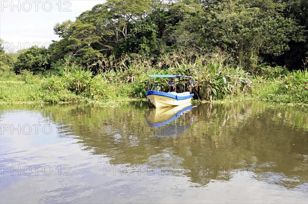 Granada, Nicaragua, A boat glides gently on the calm Nicaragua Lake surrounded by dense vegetation,