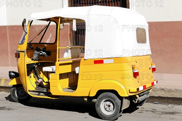 Leon, Nicaragua, Yellow motorbike taxi (Tuc Tuc) parked in front of a white wall, Central America,