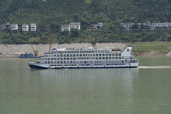 Cruise ship on the Yangtze River, A large white cruise ship is anchored in the river near green