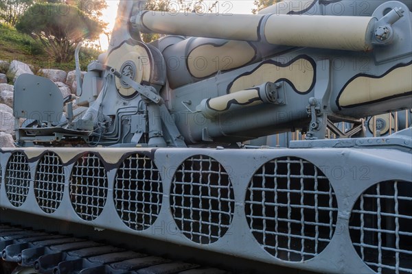 Closeup of camouflaged army tank with side view of vents above track and chair on rear portion of