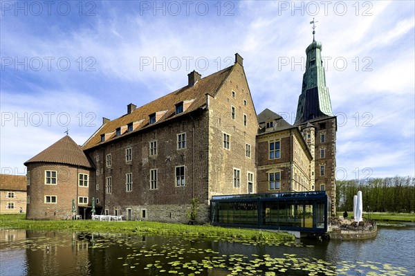 View over wide moat to historic moated castle from Renaissance Schloss Raesfeld, water lilies in