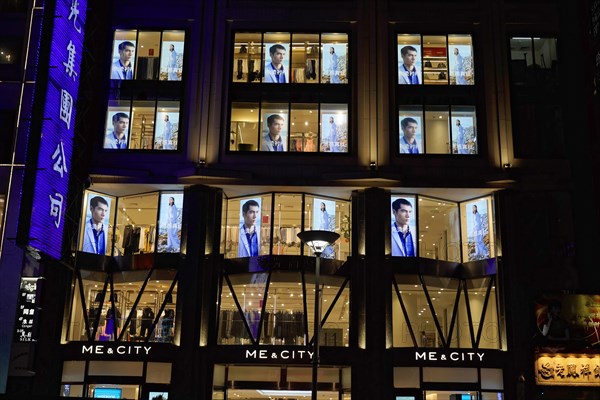 Shanghai by night, China, Asia, Night view of an illuminated shop with fashion presentation in the