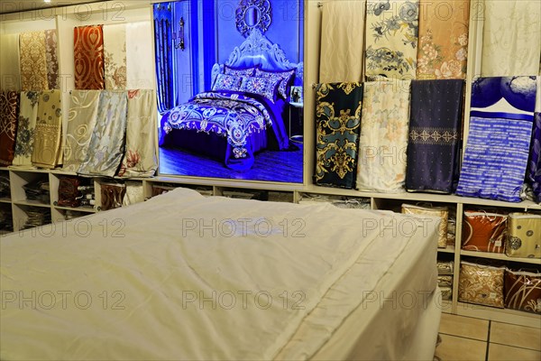 Silk factory Shanghai, A bed surrounded by patterns and fabric panels in a textile shop, Shanghai,