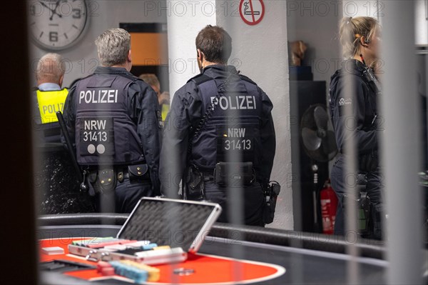 Police officers look at evidence on a casino table during an investigation, The Cologne police led