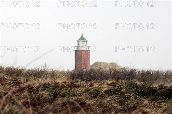 Lighthouse of Kampen, Small brick lighthouse stands between dunes under a cloudy sky, Sylt, North