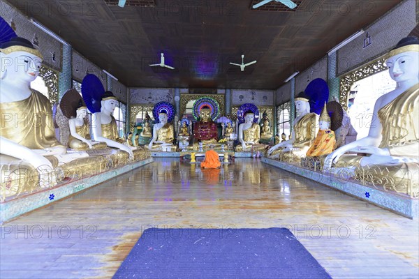 Shwedagon Pagoda, Yangon, Myanmar, Asia, A monk meditates between golden Buddha statues in a